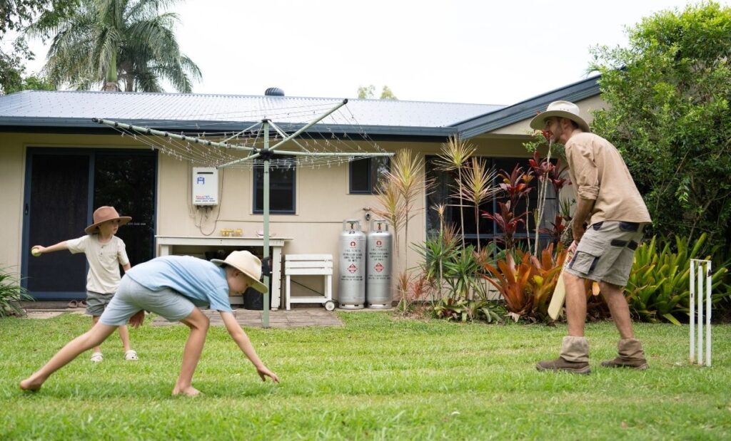 Padre juega al críquet en el jardín con sus hijos
