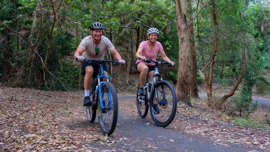 Hombre y mujer montando en bicicleta a través del arbusto