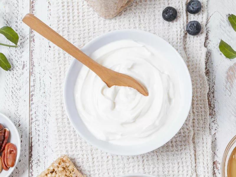 tazón de yogur blanco con cuchara, ideal para desayuno o merienda