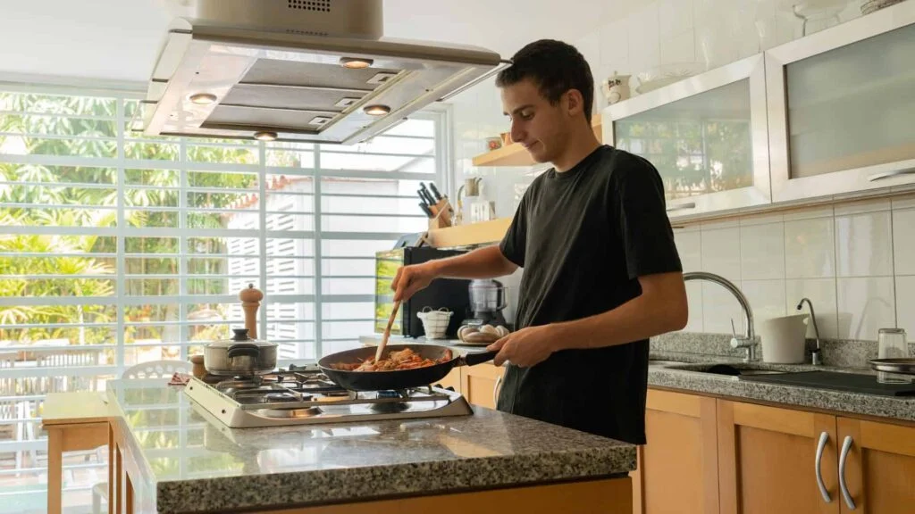 Adolescente cocinando un salteado de manera independiente en la cocina