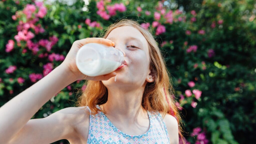 Niña bebiendo leche al aire libre