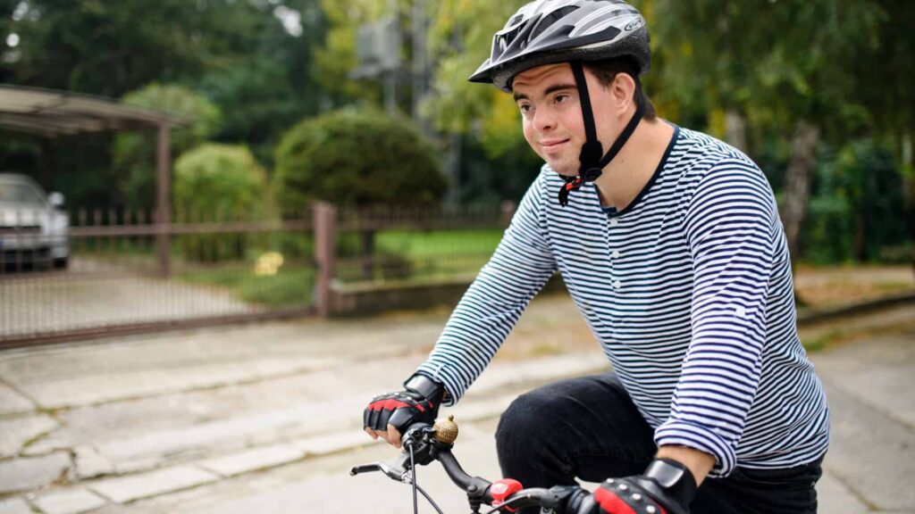 Joven con síndrome de Down montando su bicicleta en una calle local
