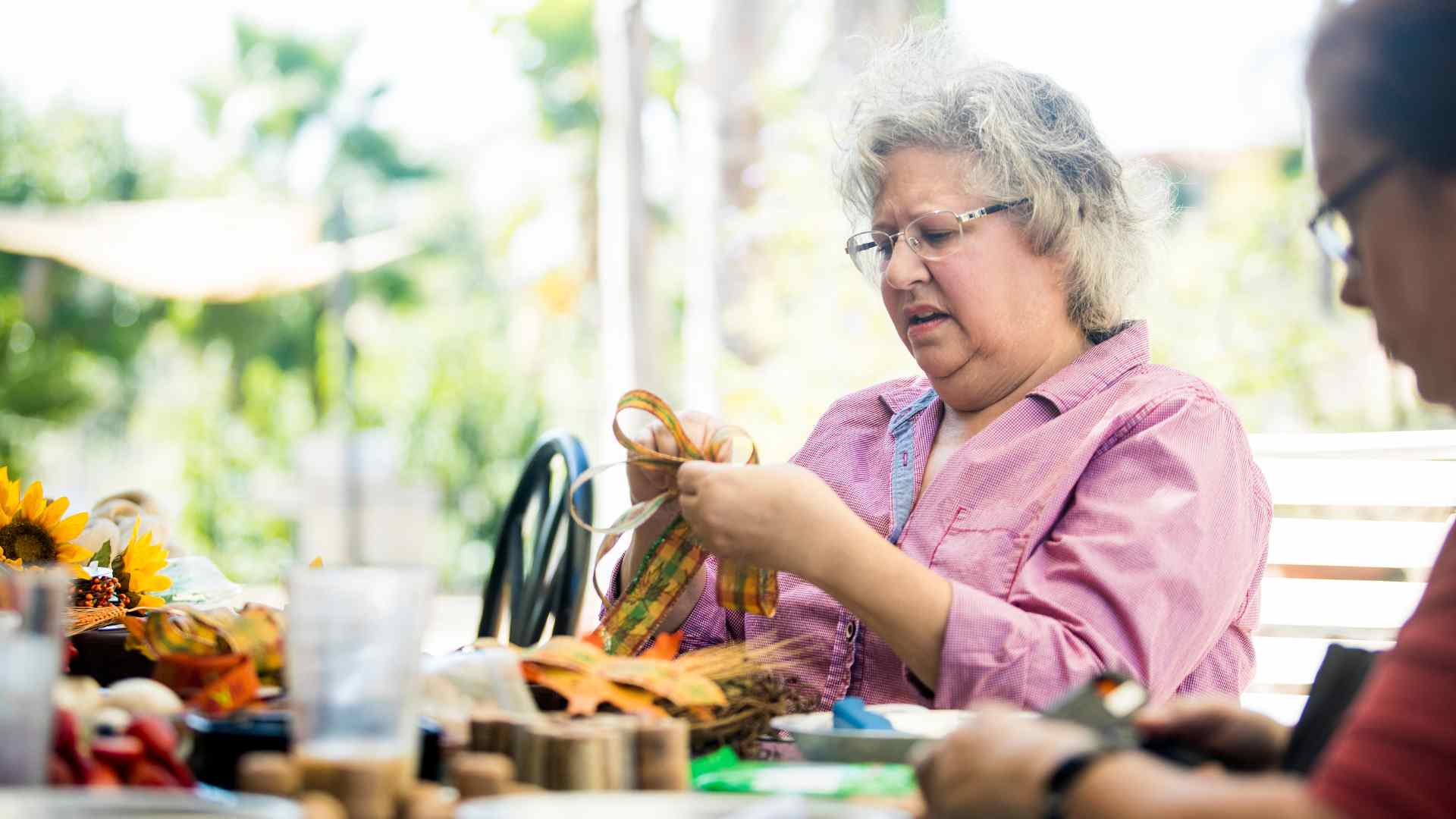 Mujer mayor haciendo manualidades en una mesa con amigos