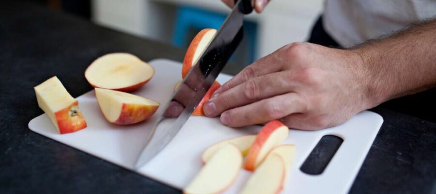 Persona cortando rodajas de manzana en una tabla de cortar