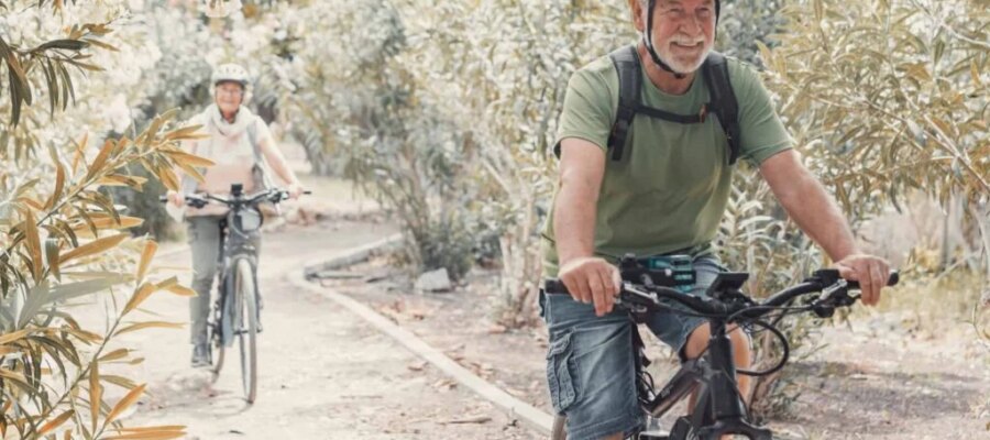 Una pareja mayor pasea en bicicleta por un sendero natural