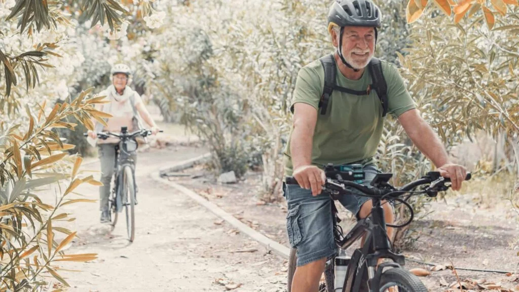 Una pareja mayor pasea en bicicleta por un sendero natural