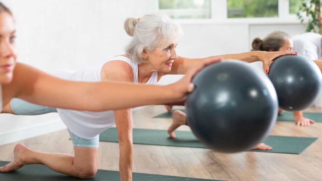 Mujeres maduras realizan ejercicio de pilates en una colchoneta