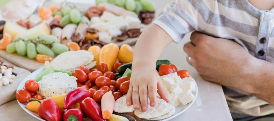 Un niño pequeño alcanza una galleta en un plato de verduras