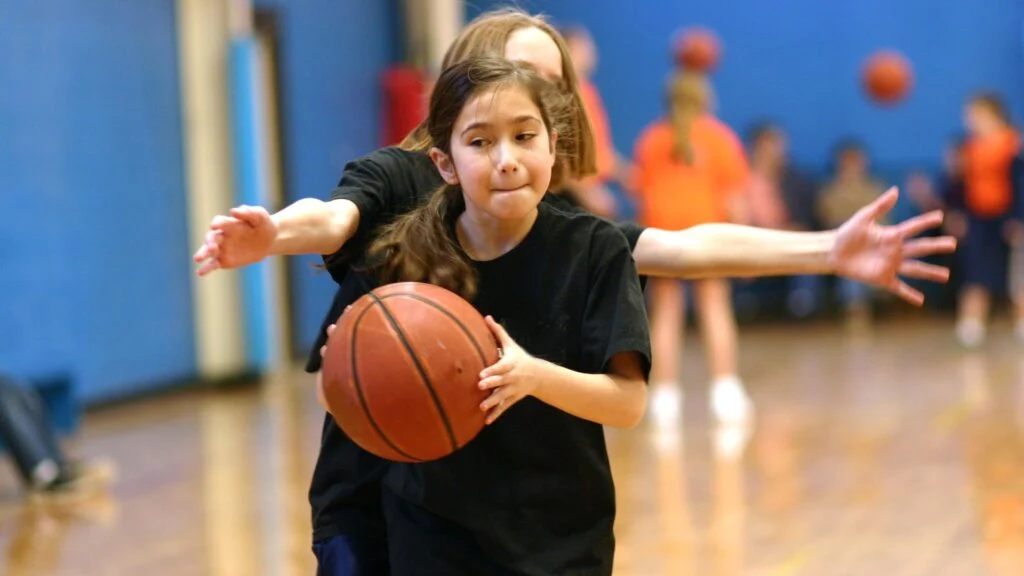 Dos niñas jugando baloncesto en interiores