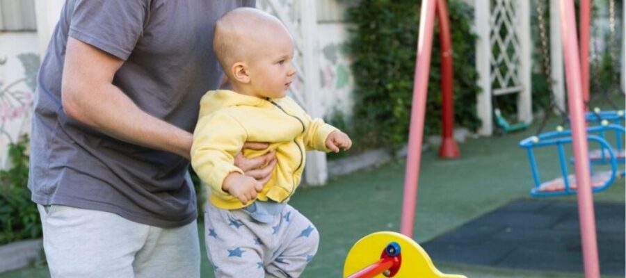 Padre levanta a su hijo pequeño en el parque infantil