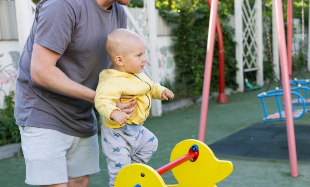 Padre levanta a su hijo pequeño en el parque infantil